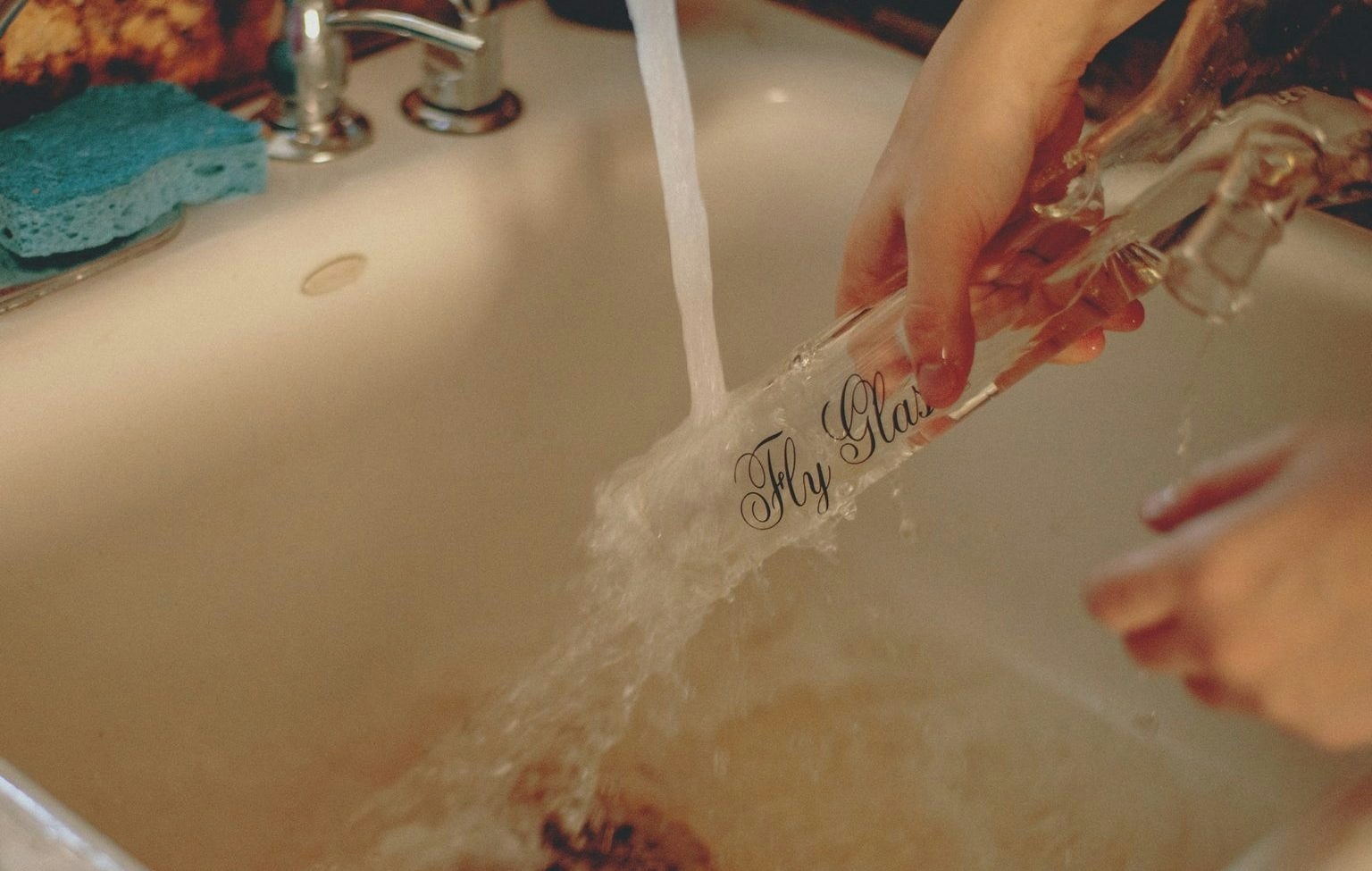 woman cleaning a bong in the sink