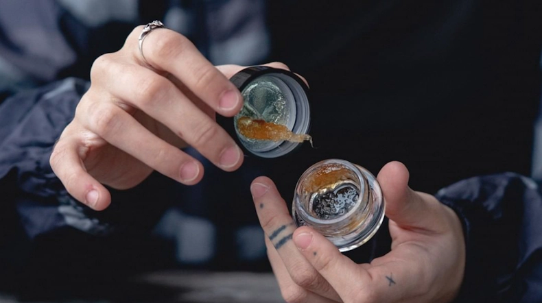 A persons hands holding a jar of liquid diamonds open, revealing the thick concentrate.