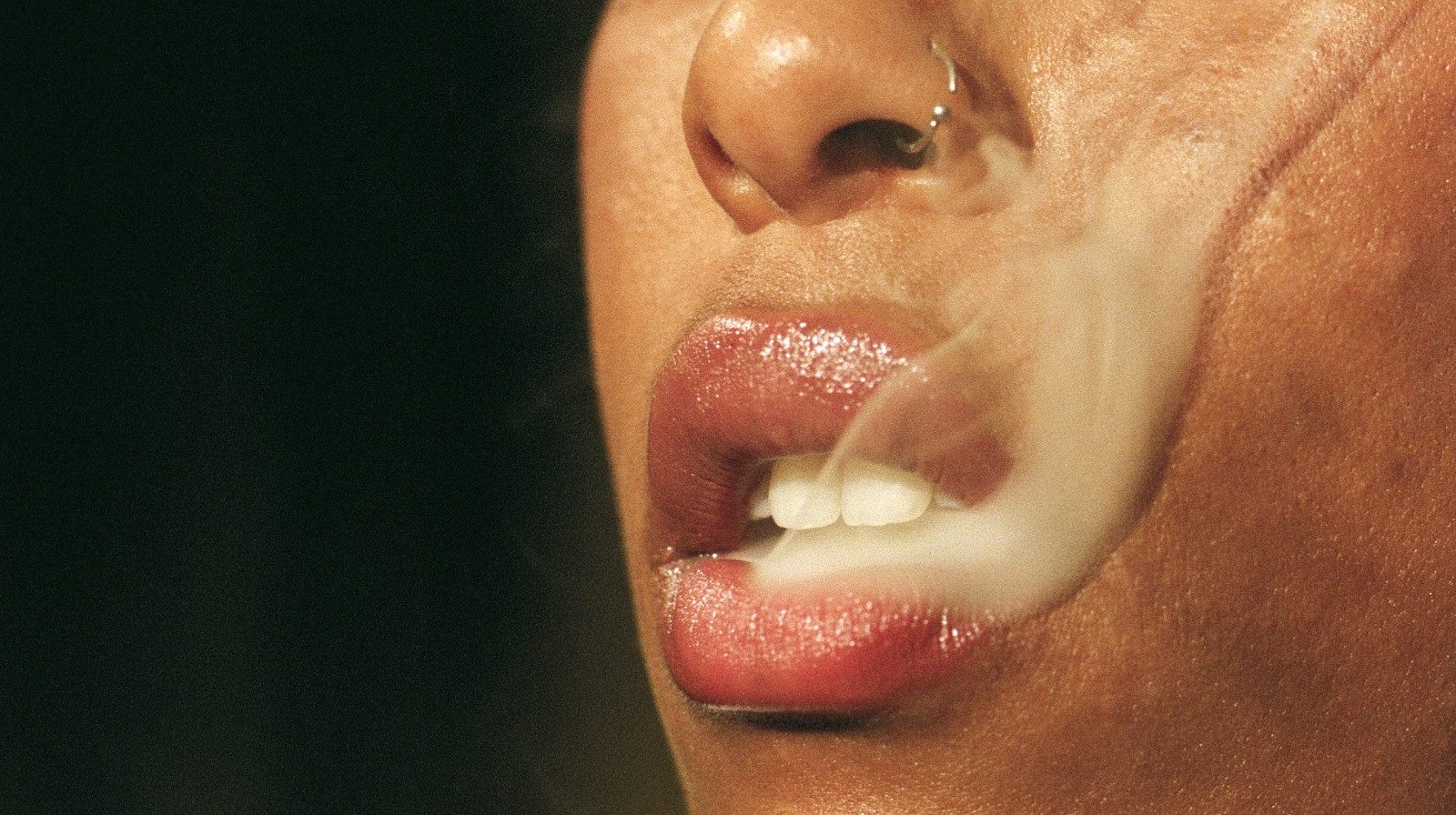 A woman's lips exhaling cannabis smoke.