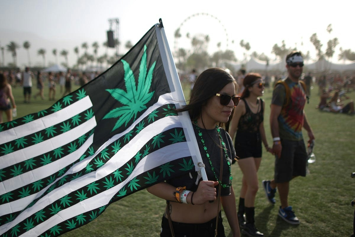 A woman carries a flag bearing marijuana symbol