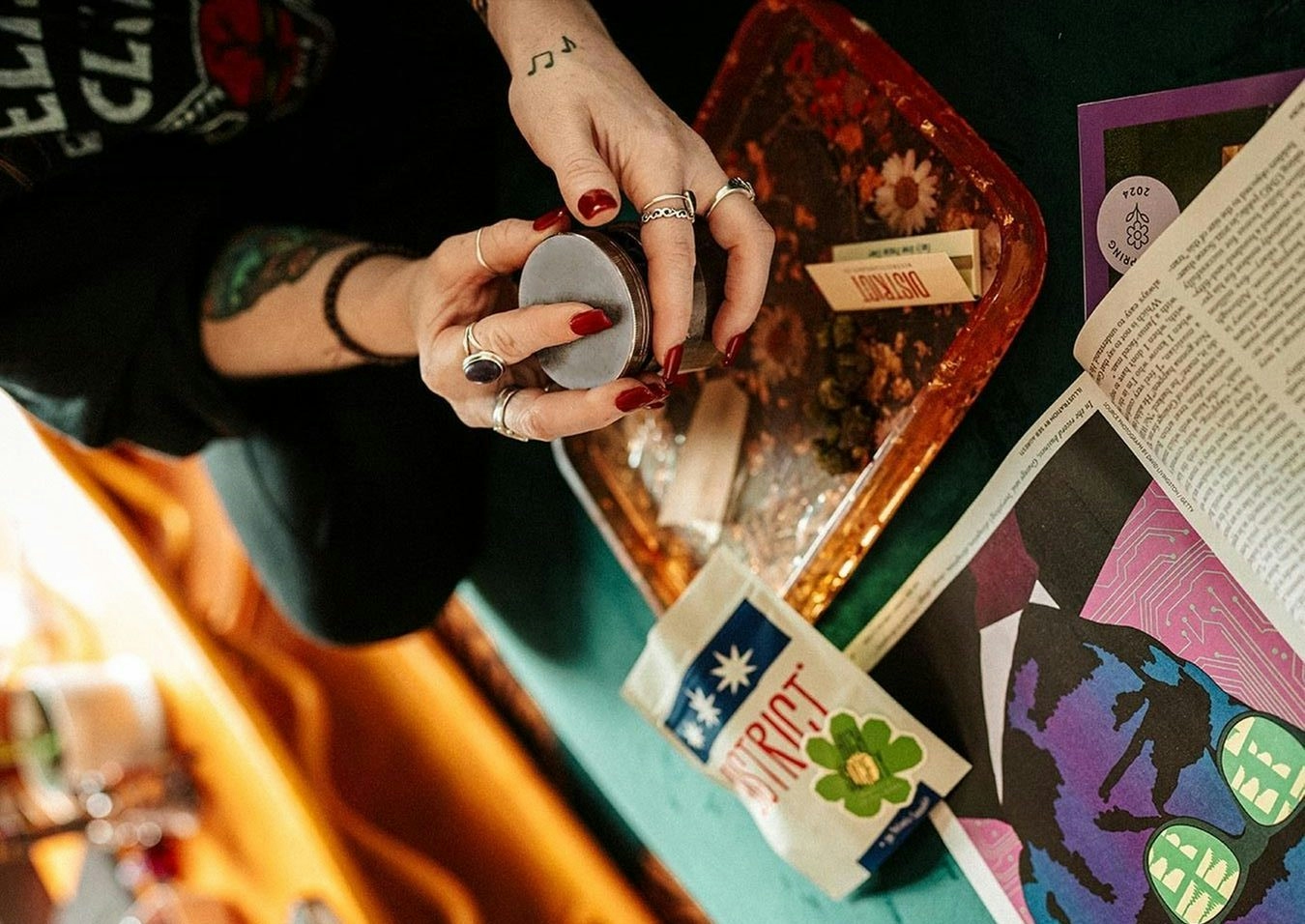 woman holding a grindr and hand rolling a joint