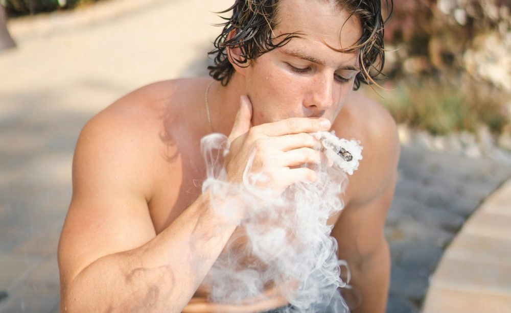 man smoking a joint by the pool
