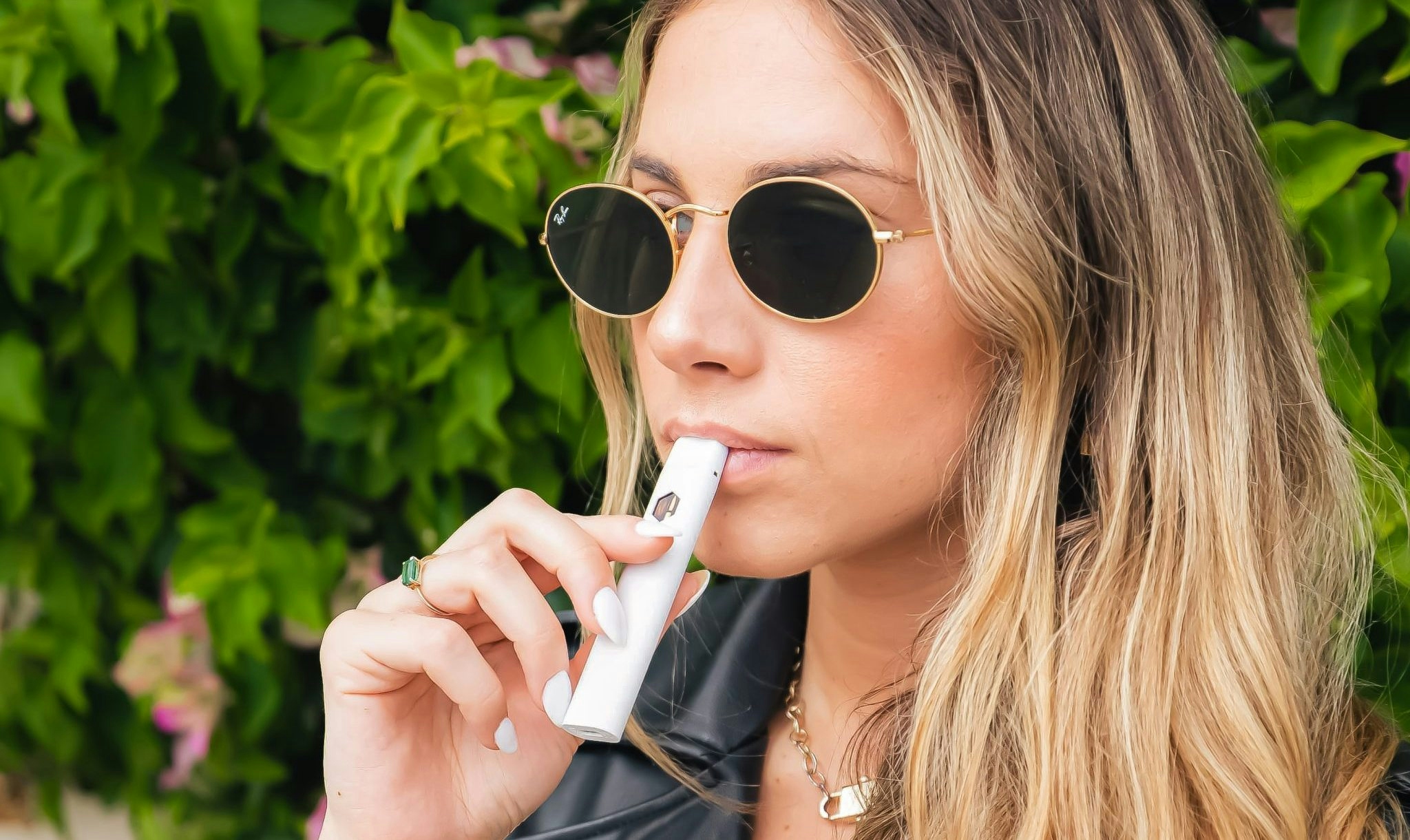 woman with black glasses smoking from a vape