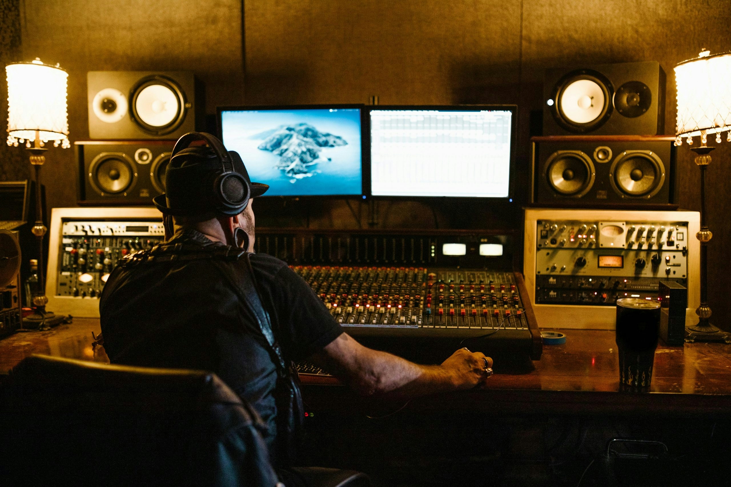 Man in black shirt wearing headphones in front of monitors