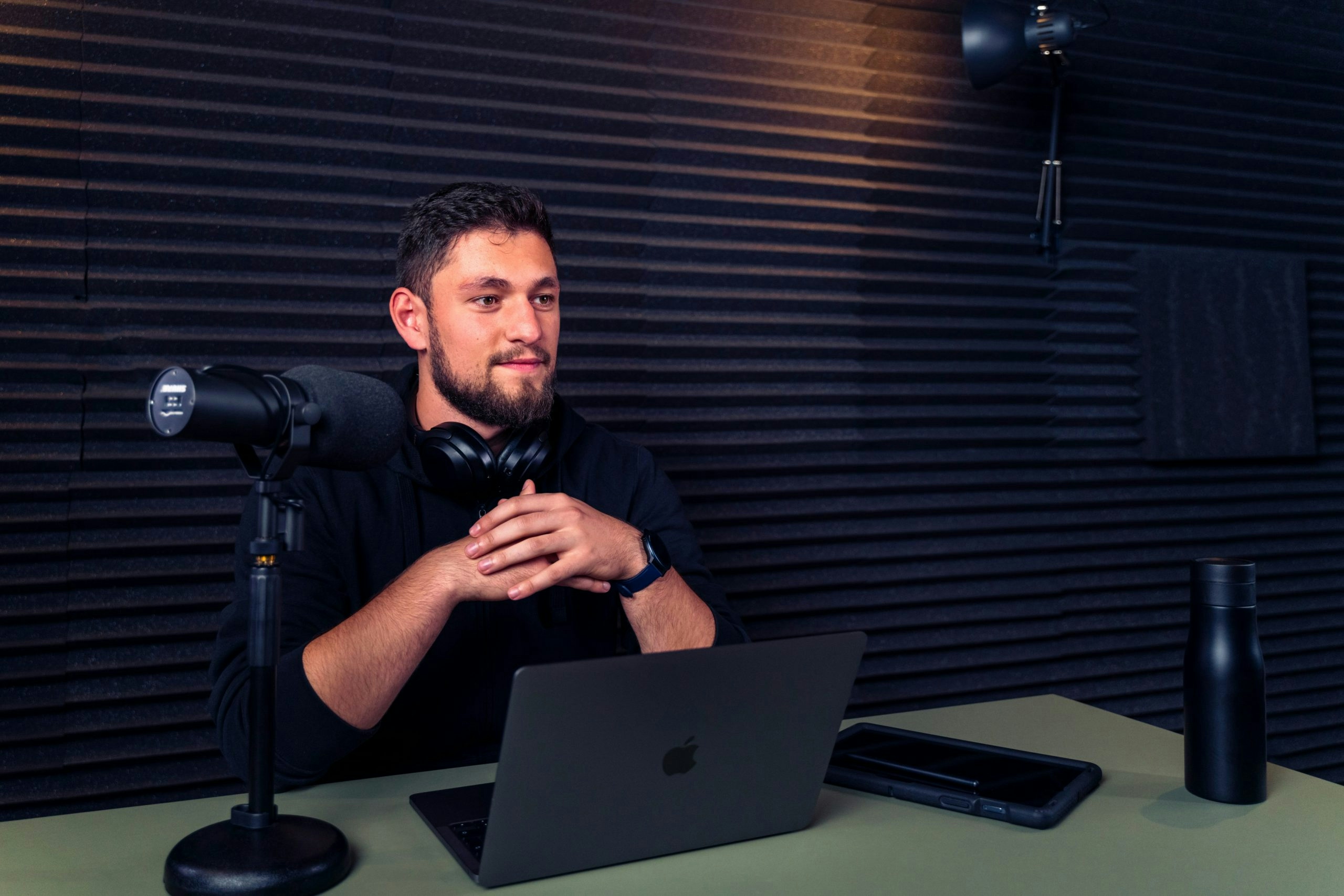 Man sitting at a desk with a laptop and microphone