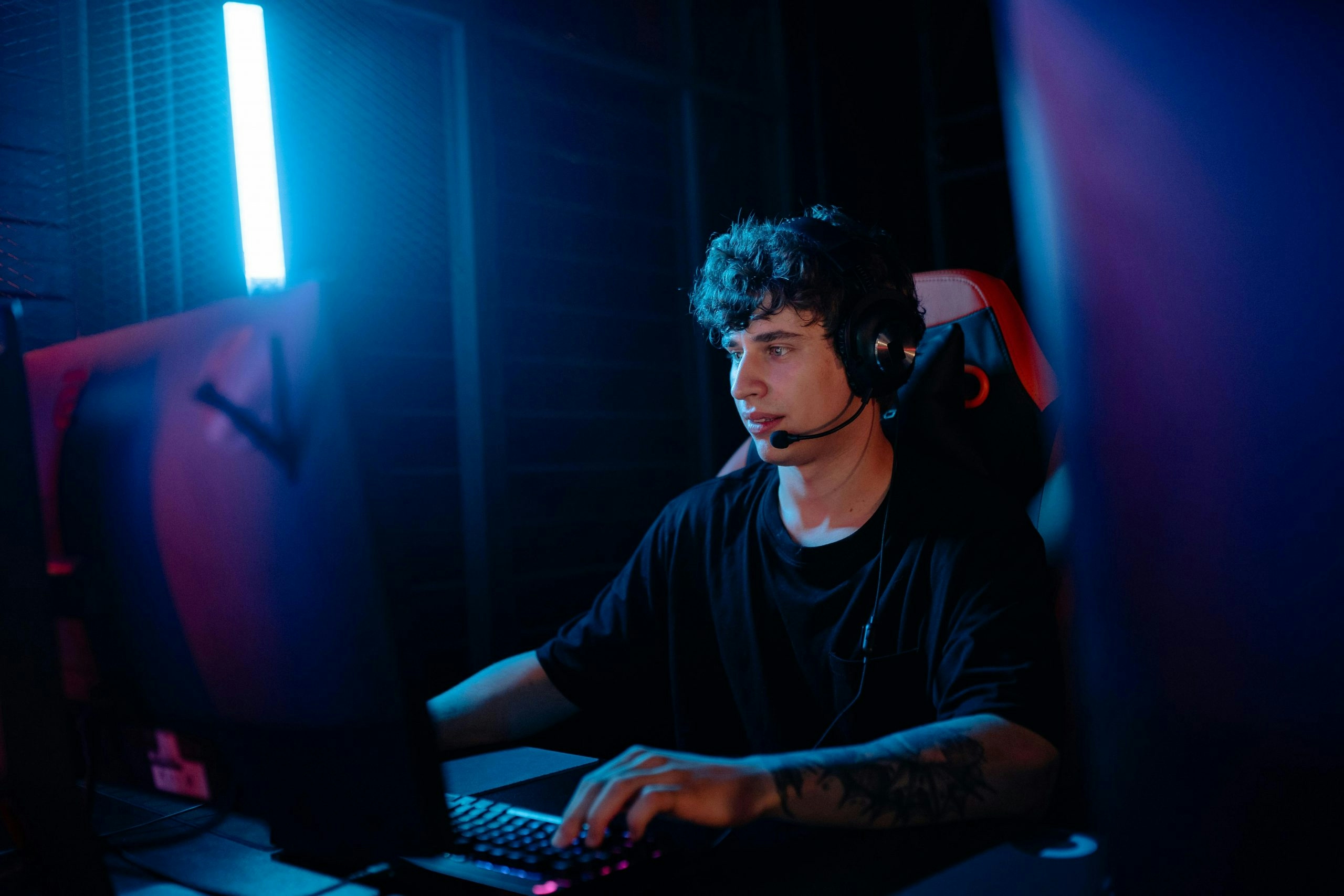 Tattooed man in a black shirt gaming on a desktop