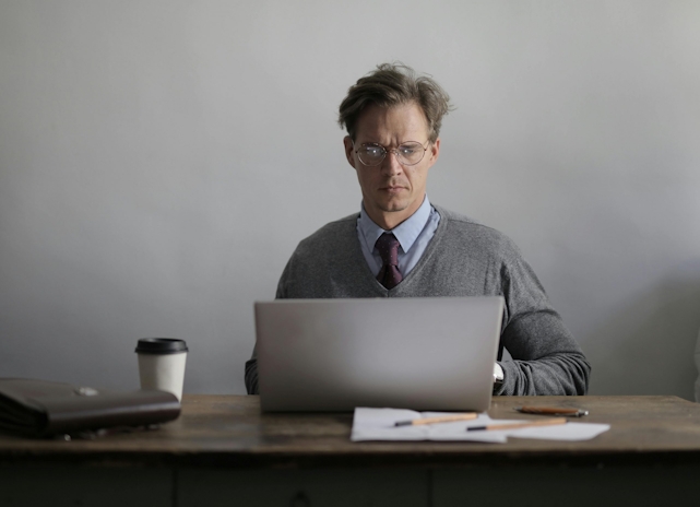 Concentrated teacher using laptop in office