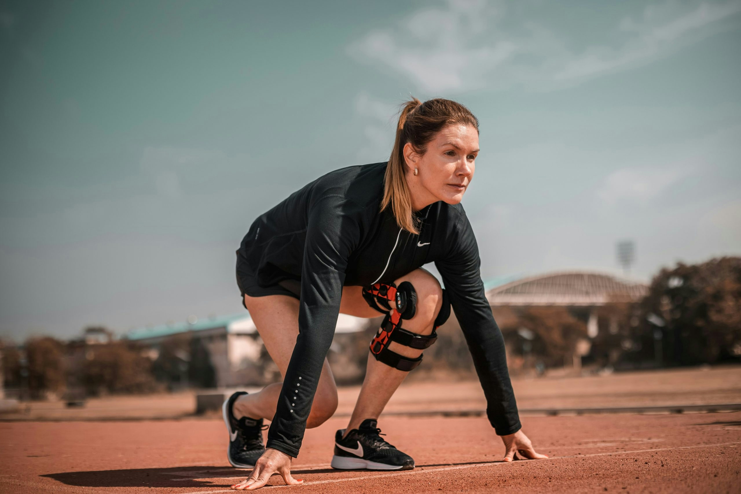 Woman crouching down to pick up a tennis ball
