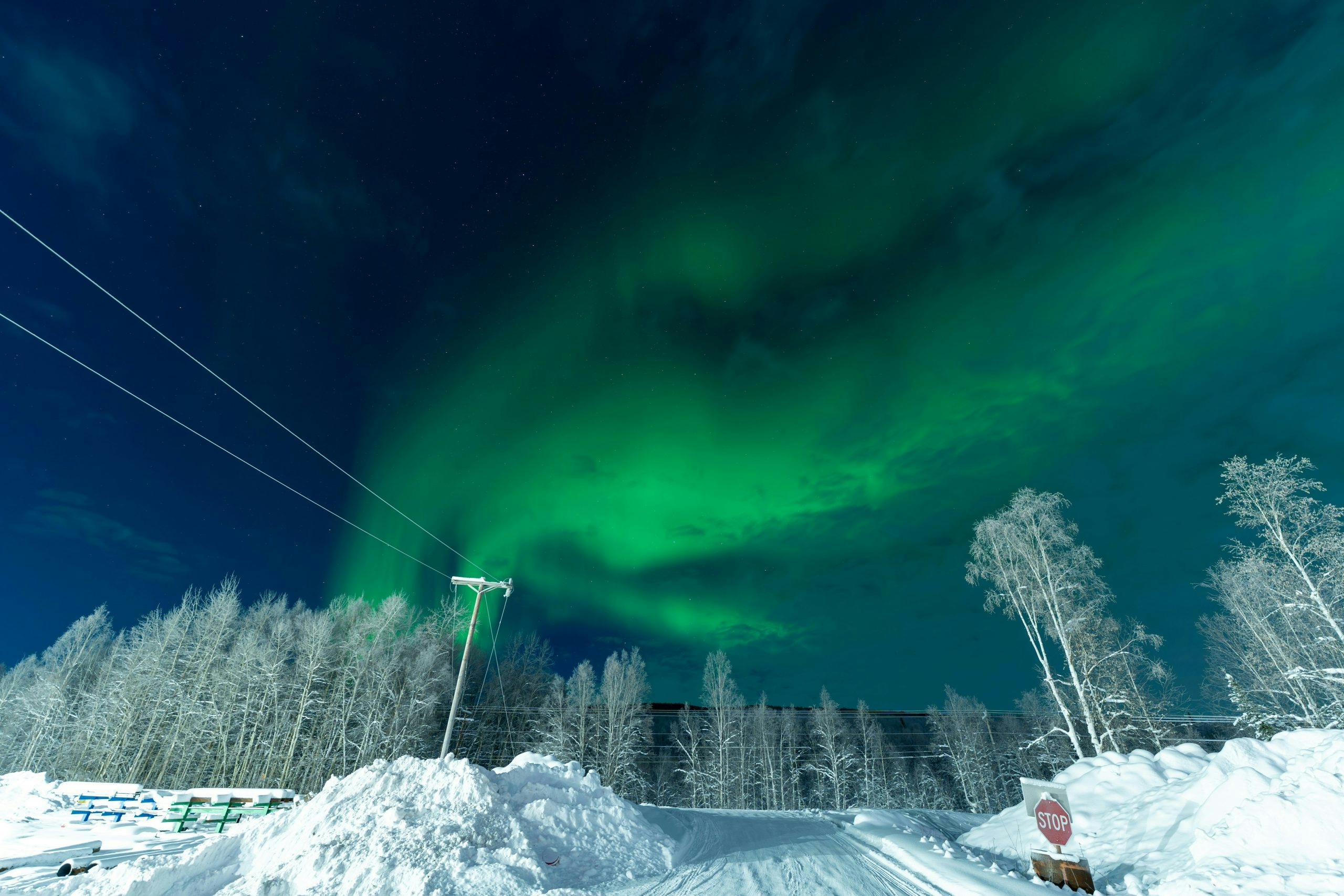 A green aurora borealis seen in the sky above a snow-covered road