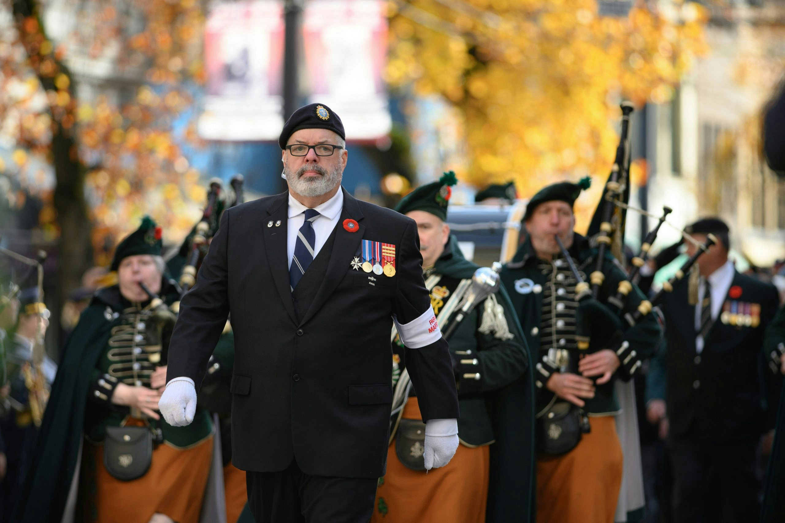 Veterans march in a parade with bagpipers.