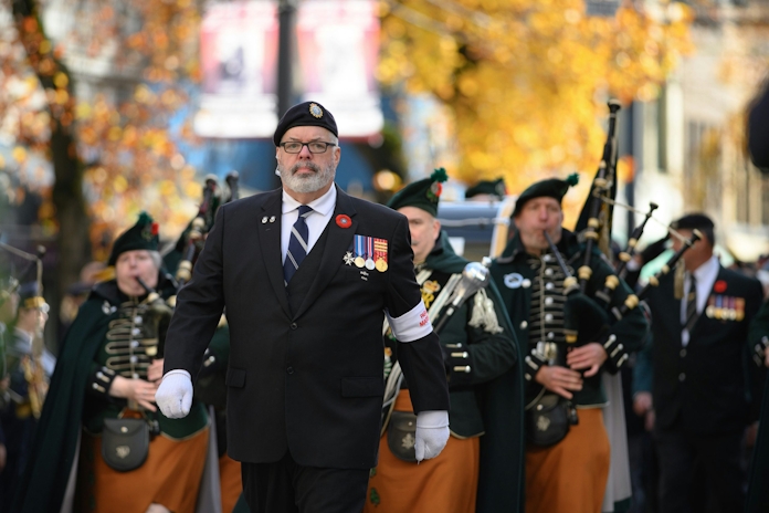 Veterans march in a parade with bagpipers.