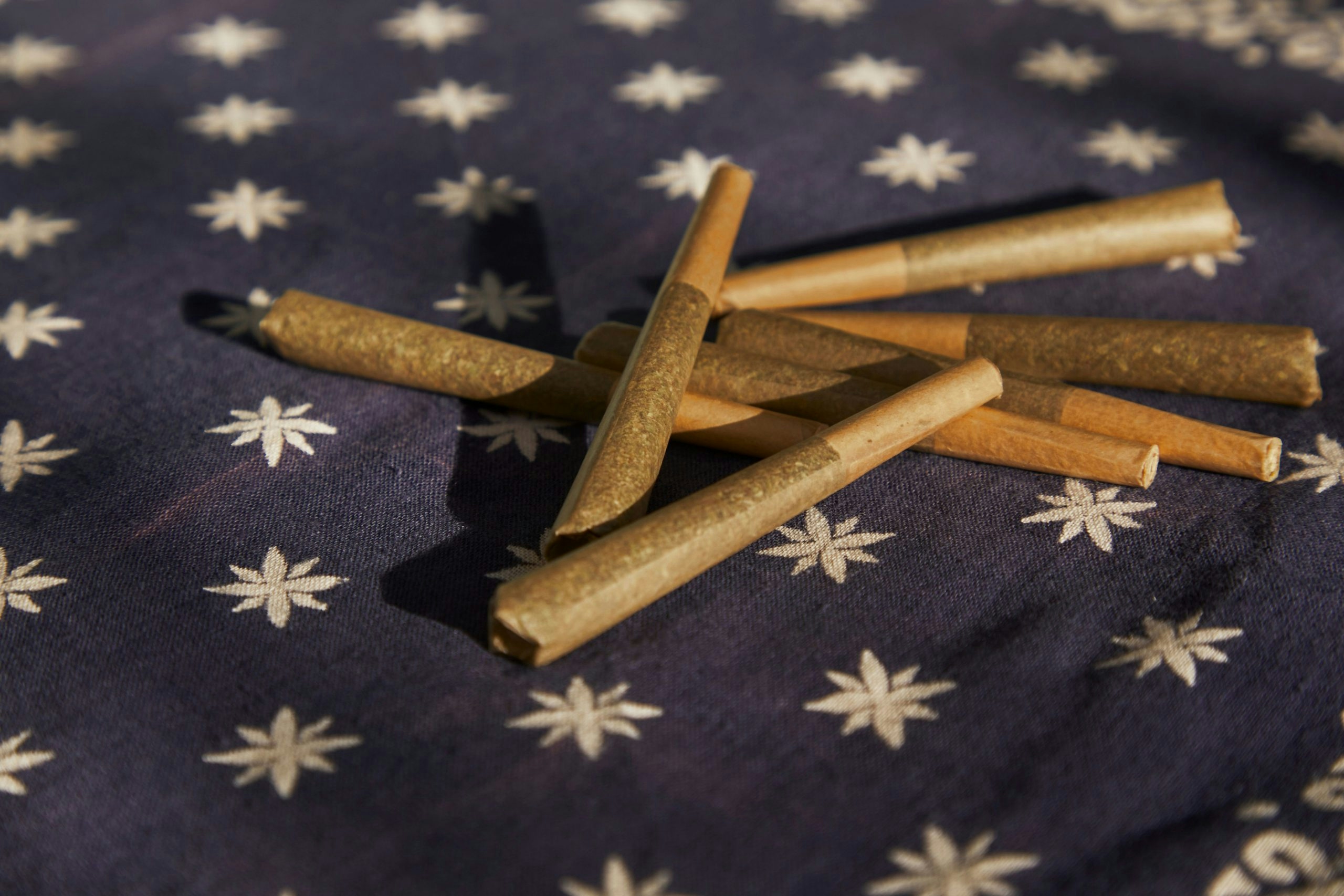 Six of the best THCA pre rolls sitting in a pile on a blue table cloth.