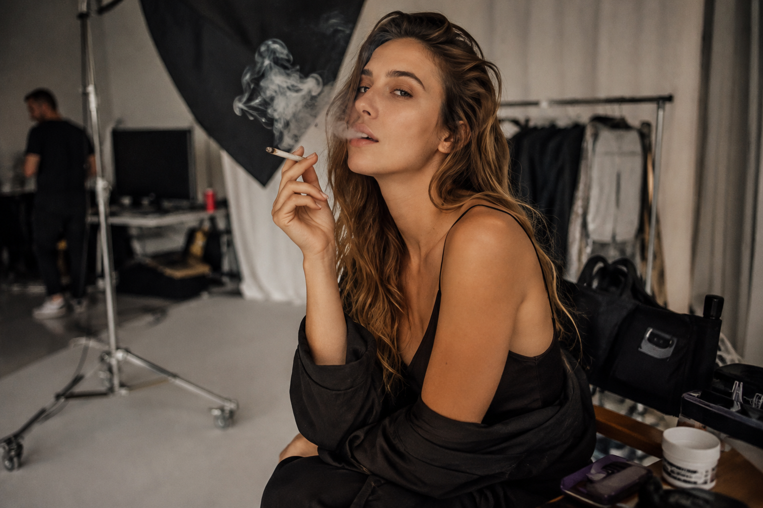 Beautiful woman posing and smoking a joint before a photography session in a professional studio
