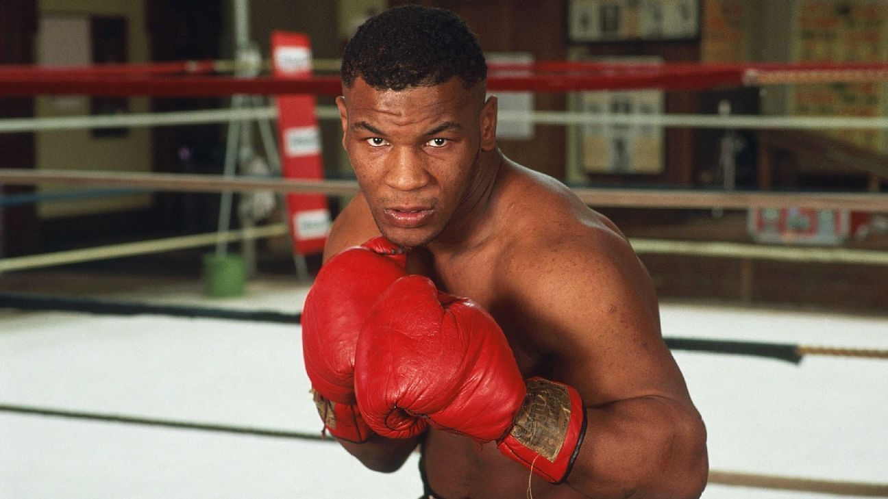 Mike Tyson in a professional boxing setting, wearing boxing gloves and preparing for a match inside the ring