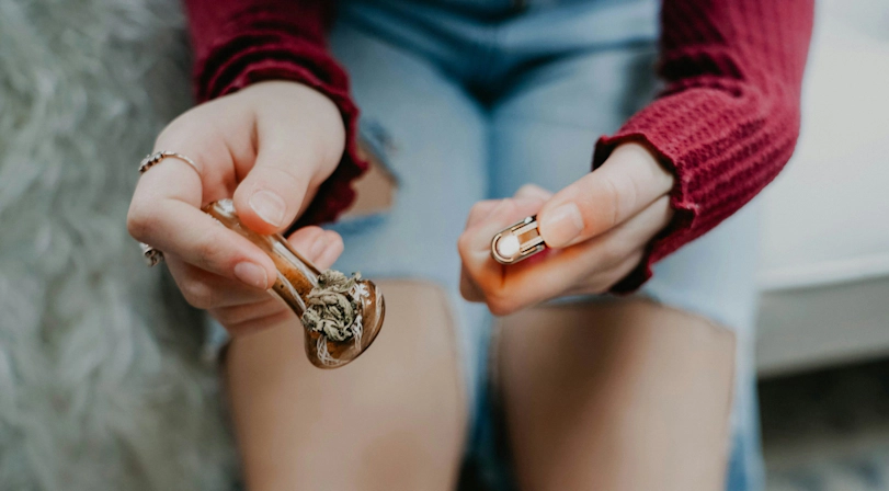 woman lighting a pipe with cannabis buds in it