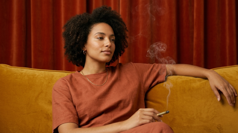 Person leaning back on a mustard velvet couch with a relaxed expression under warm light