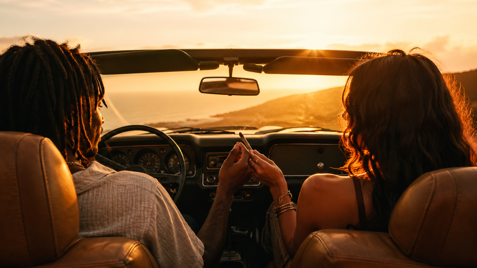 Two people sharing joint inside convertible watching ocean sunset view