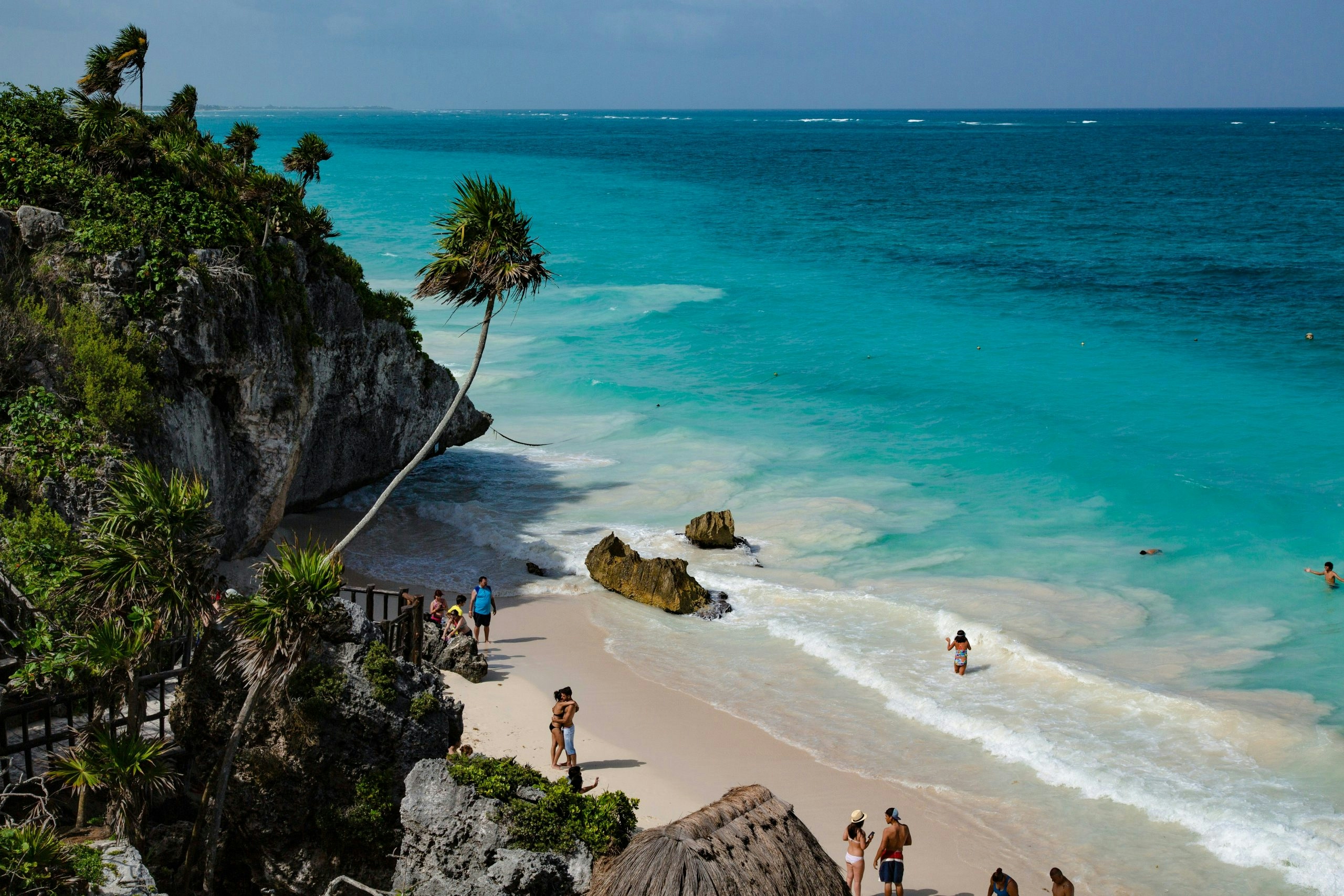 White sand beach in Tulum with turquoise Caribbean waters and swaying palm trees