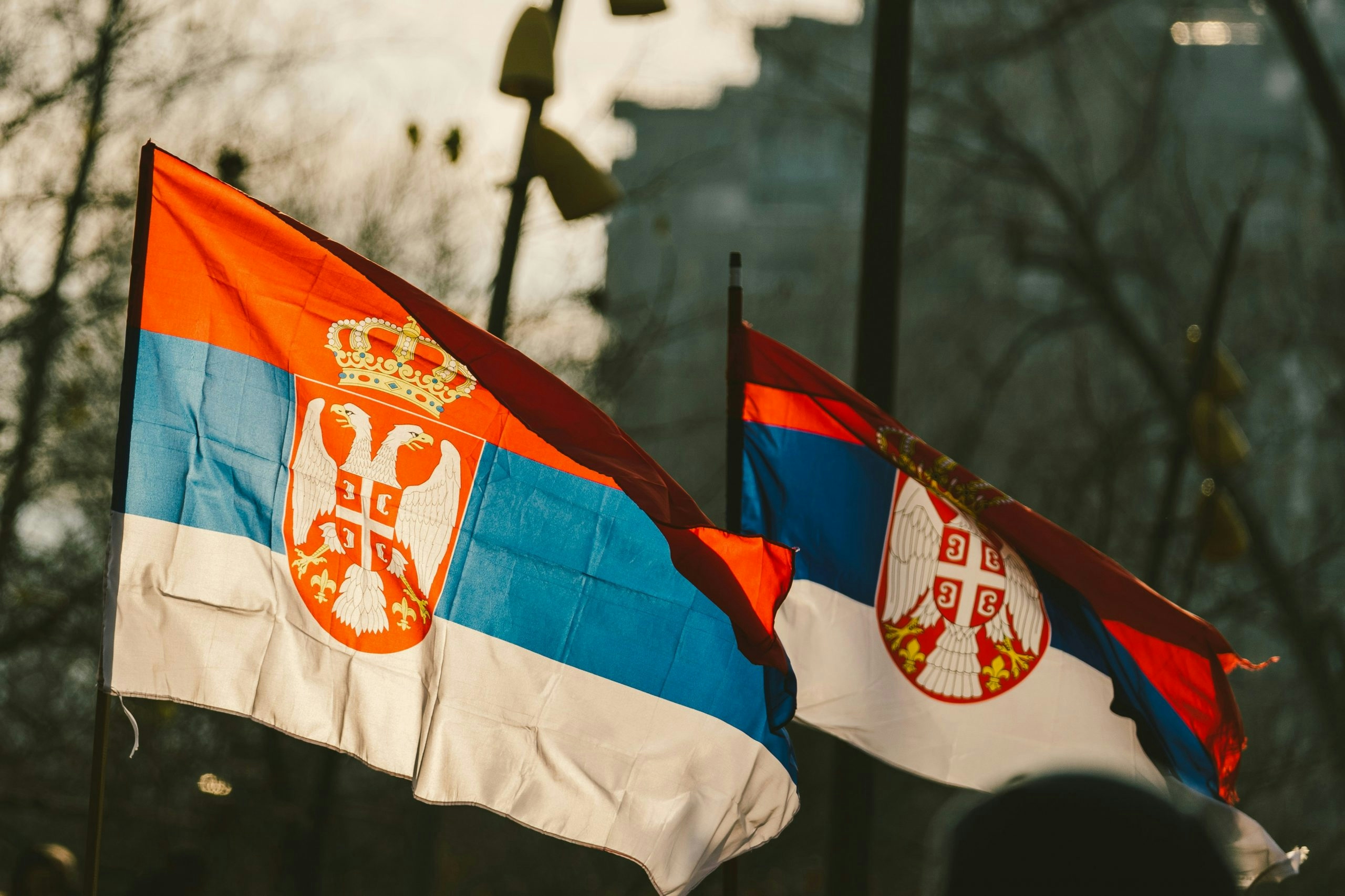 The national flag of Serbia displayed against a clear sky