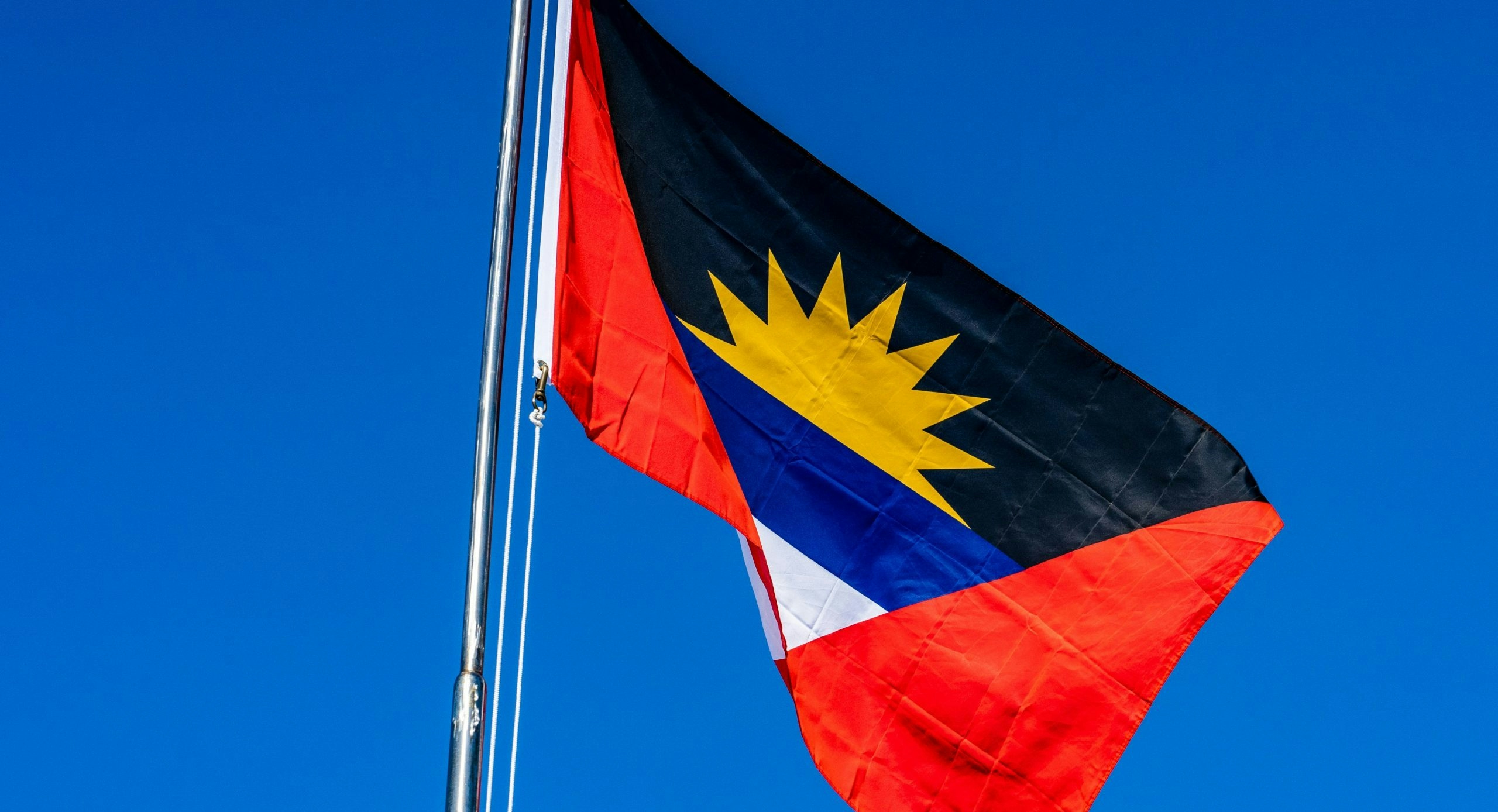 he flag of Antigua and Barbuda overlooking a tropical Caribbean landscape