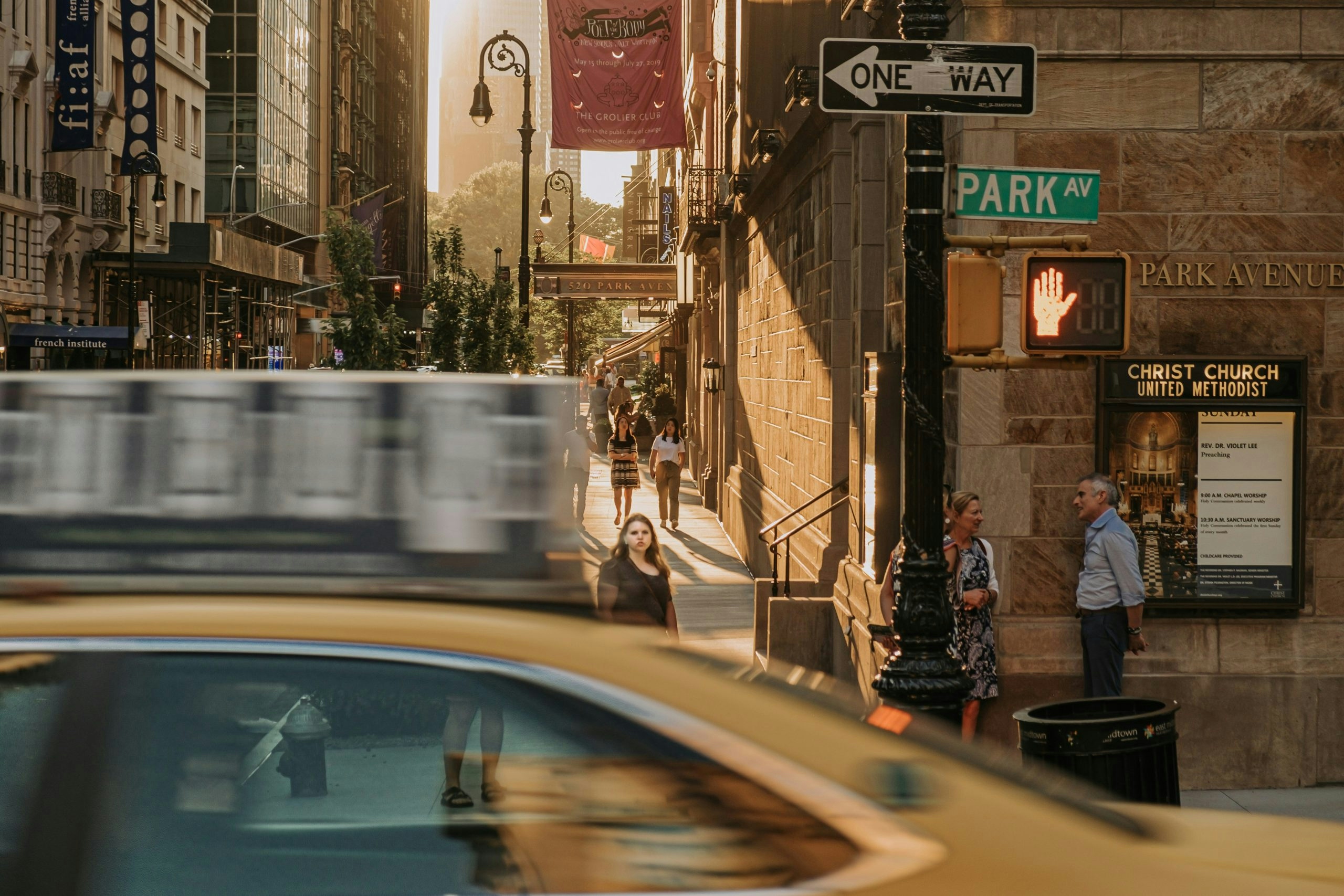 Classic yellow New York City taxi driving down a busy Manhattan street