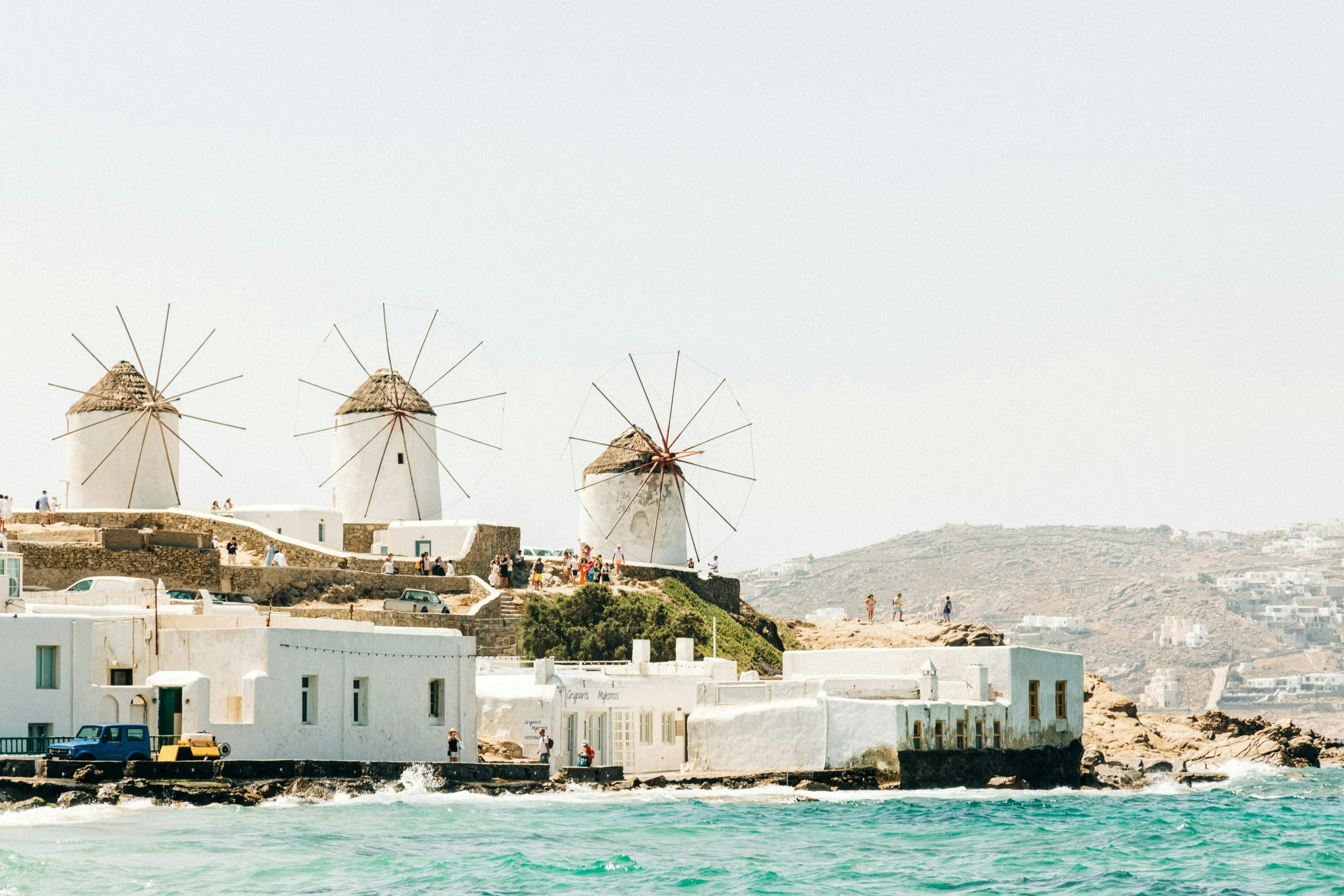 Traditional windmills in Mykonos against a backdrop of blue sea and white architecture