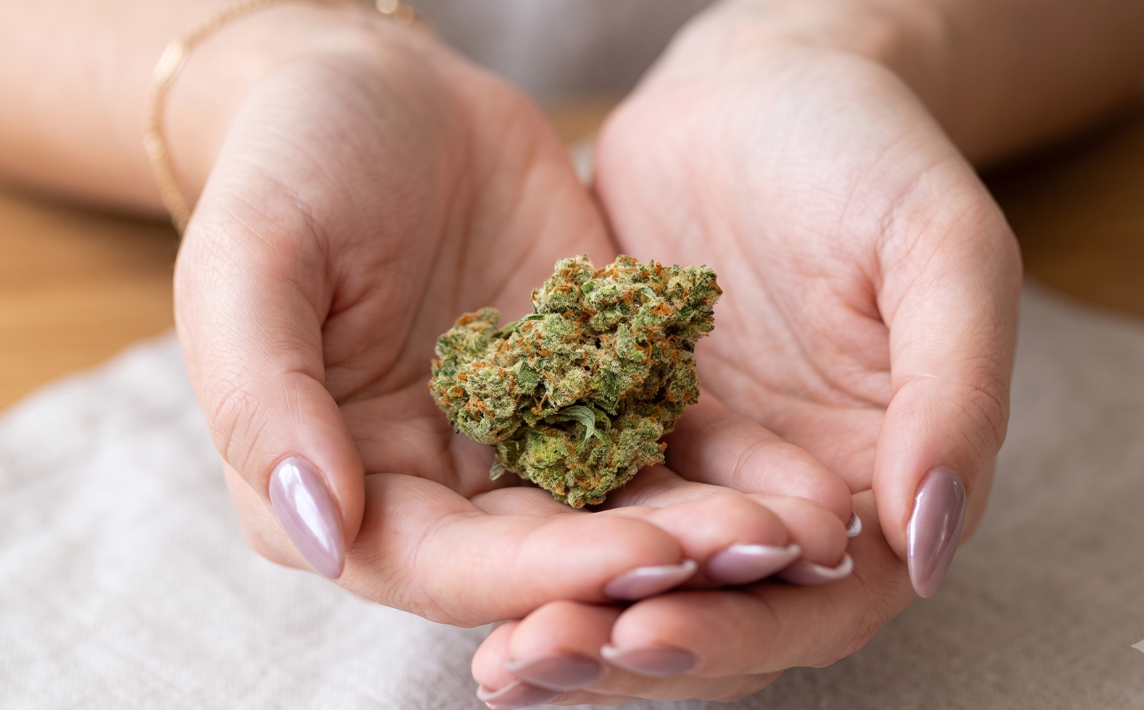 Hand holding a premium Candy Gas cannabis bud covered in frosty trichomes.
