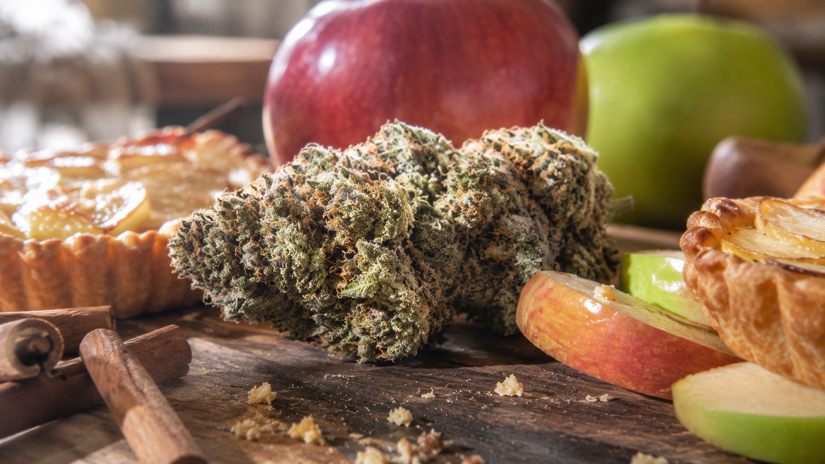 Apple Tartz cannabis buds displayed alongside fresh green and red apples to represent the strain's fruity flavor profile