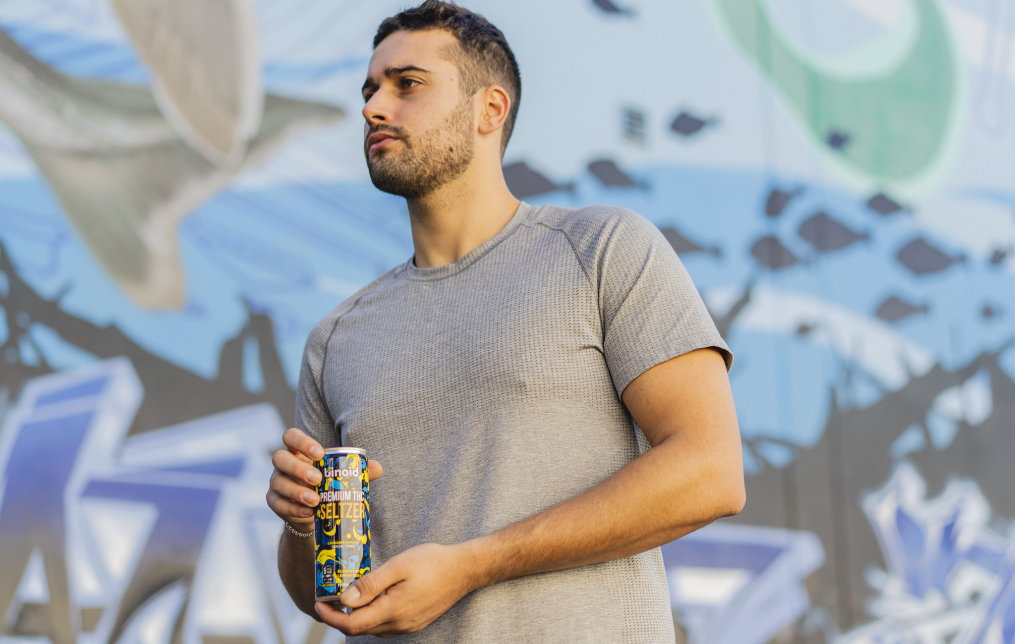 Man holding a can of Binoid Good Vibes infused beverage in a relaxed outdoor setting
