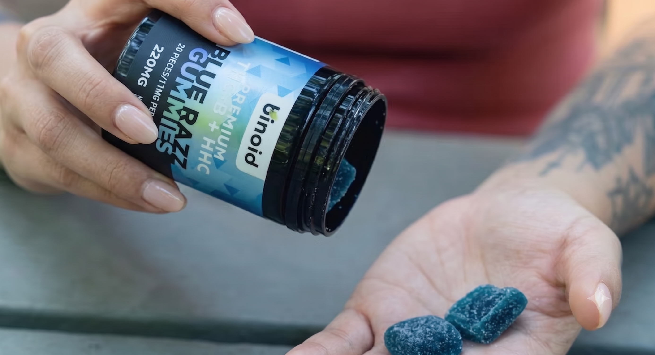Hands holding an open jar of Binoid gummies with several gummies resting in the palm