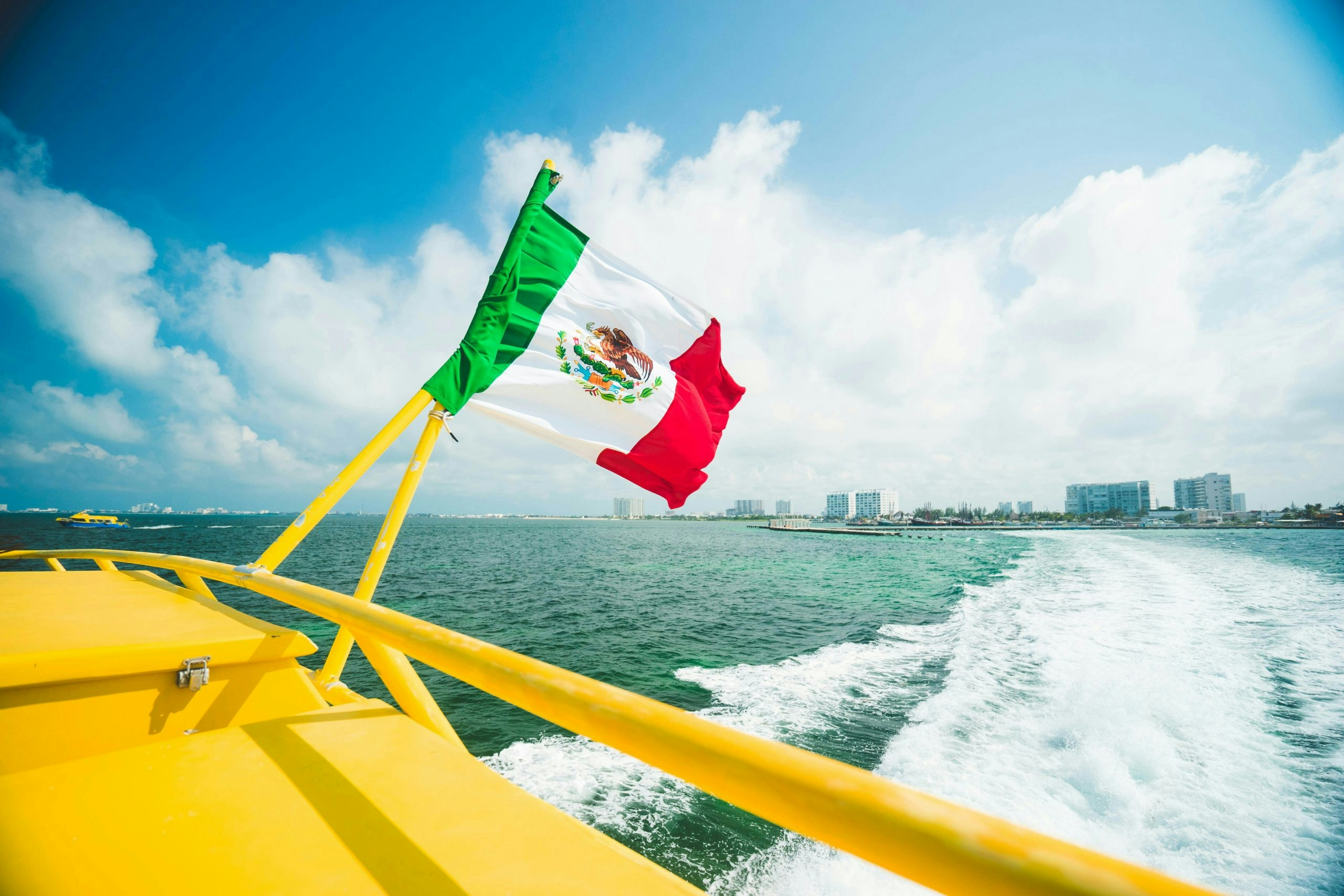 Boat with the Mexican flag sailing near Cancun