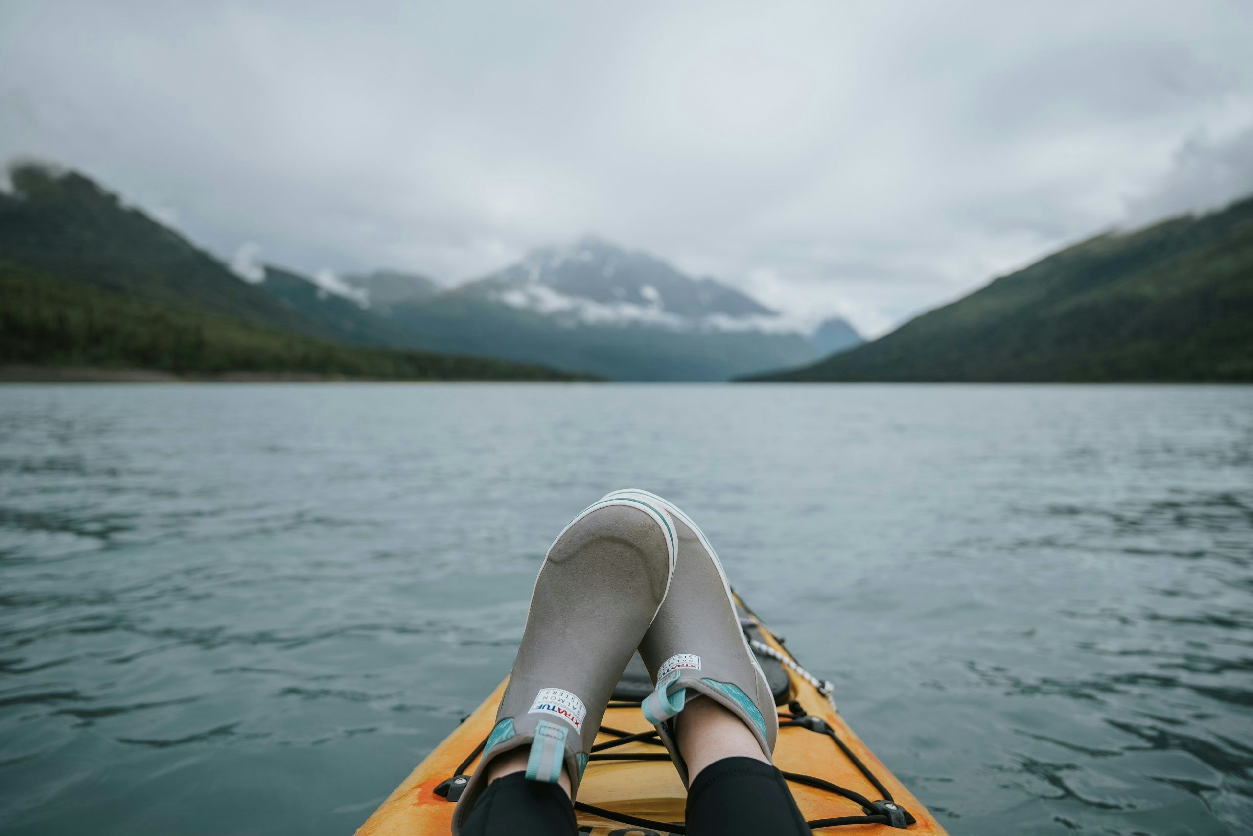 Feet on a boat with mountain views on an Alaska lake