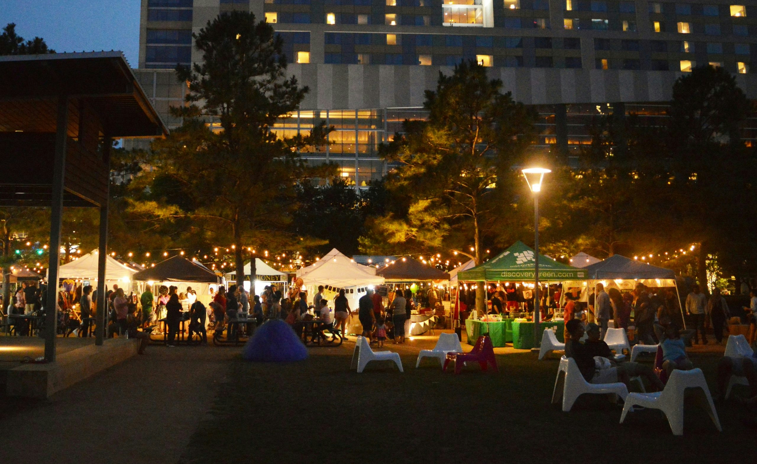 Public park in Houston filled with people under glowing evening lights