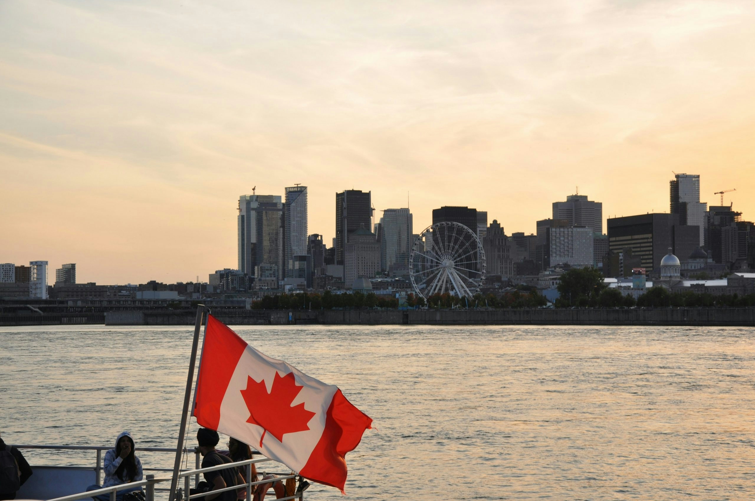 Canadian flag waving on a boat cruising in front of the Montreal skyline