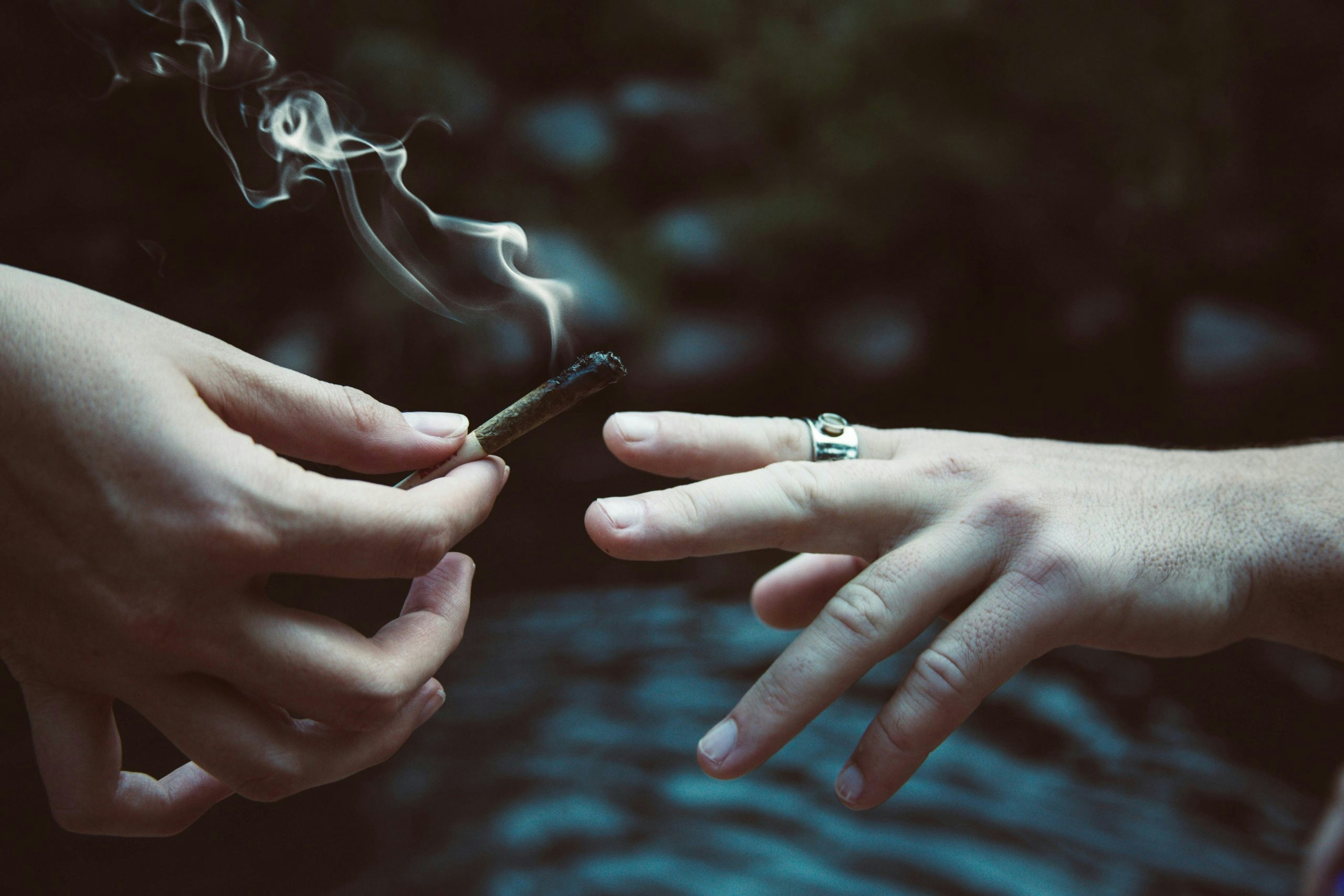 Close-up of two hands passing a weed joint.