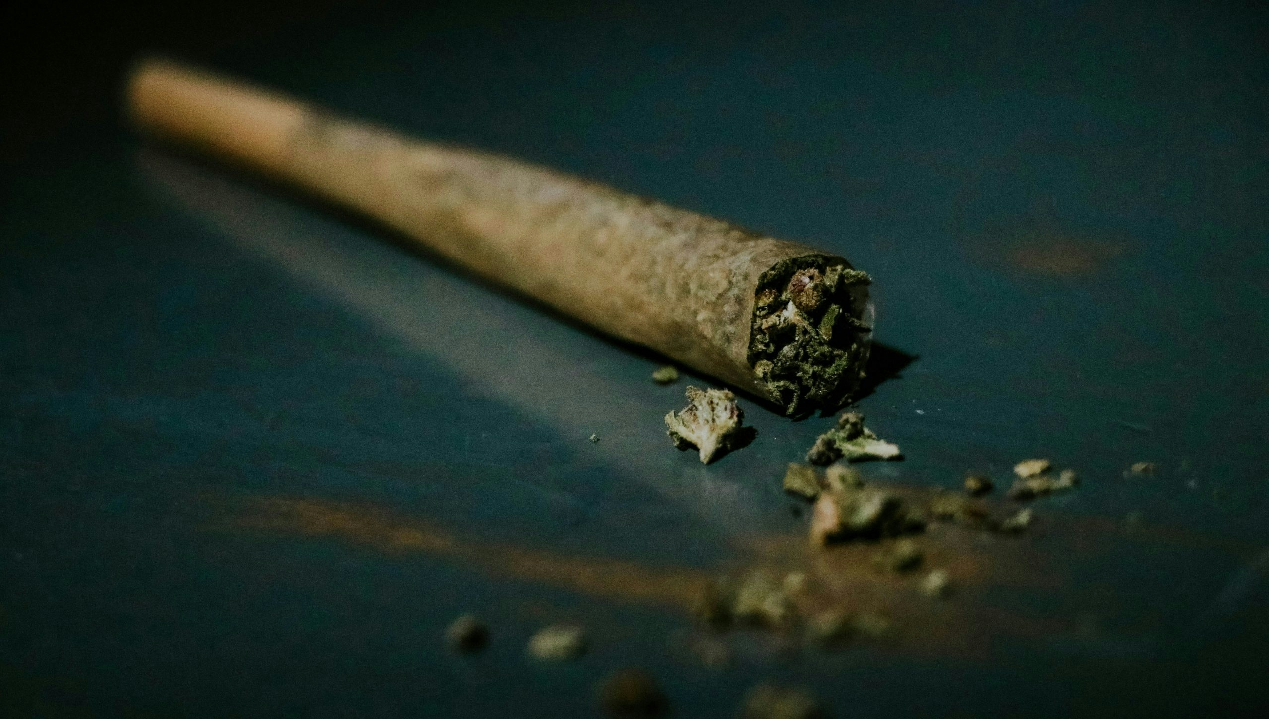 A rolled cannabis joint laying on a surface.
