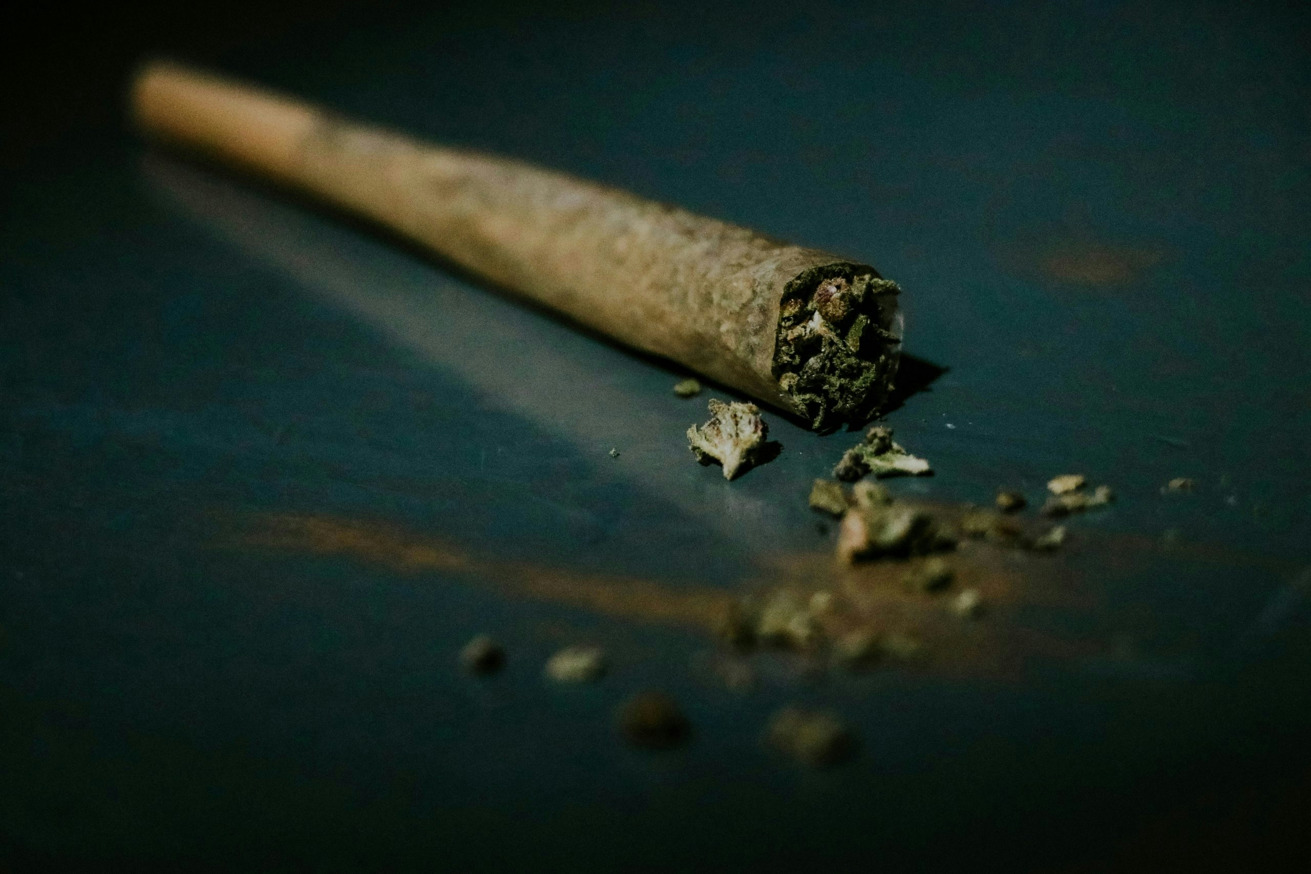 A rolled cannabis joint laying on a surface.