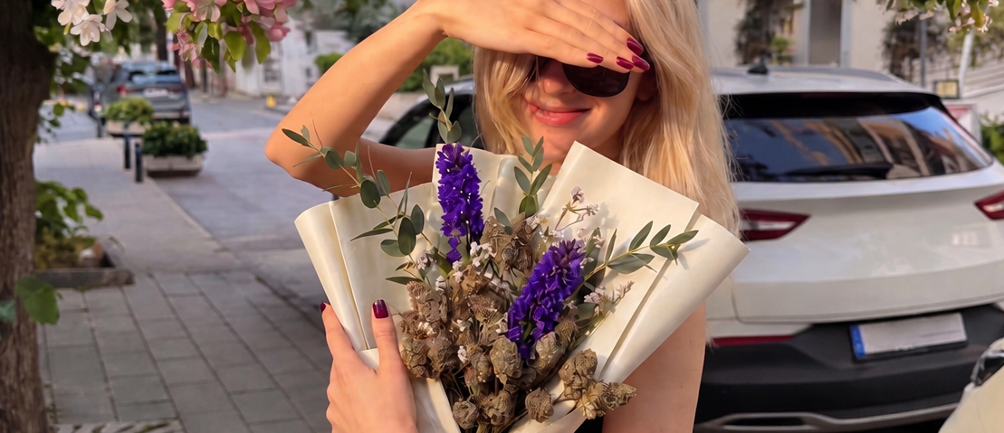 Woman posing with an elegant bouquet featuring purple flowers and cannabis buds