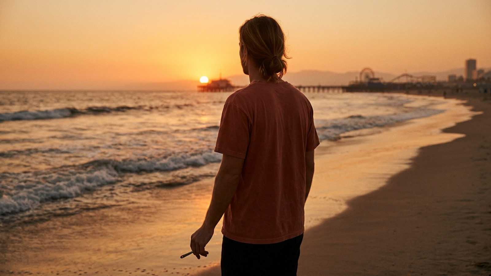 Back view of person enjoying cannabis joint on beach during sunset