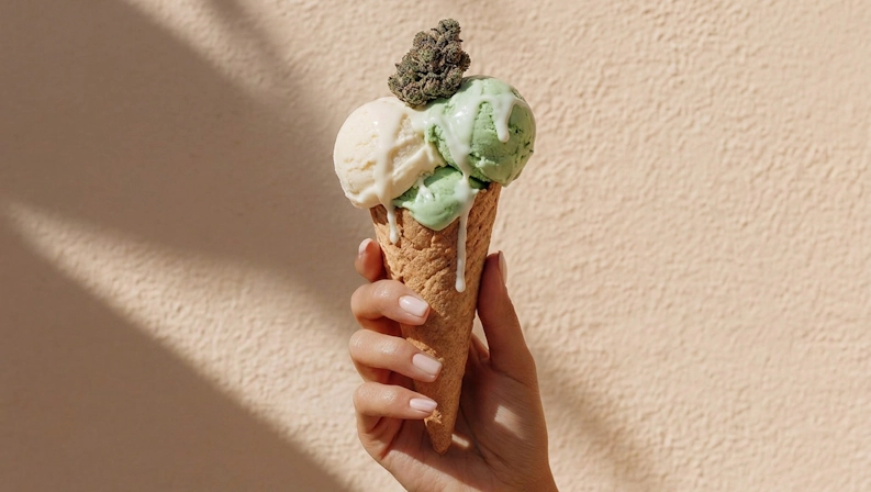 Hand holding a gelato ice cream topped with a cannabis bud