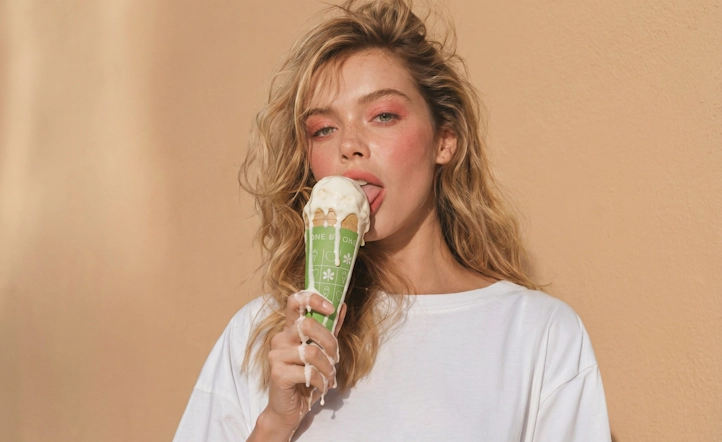 Beautiful woman holding and eating a creamy ice cream cone.