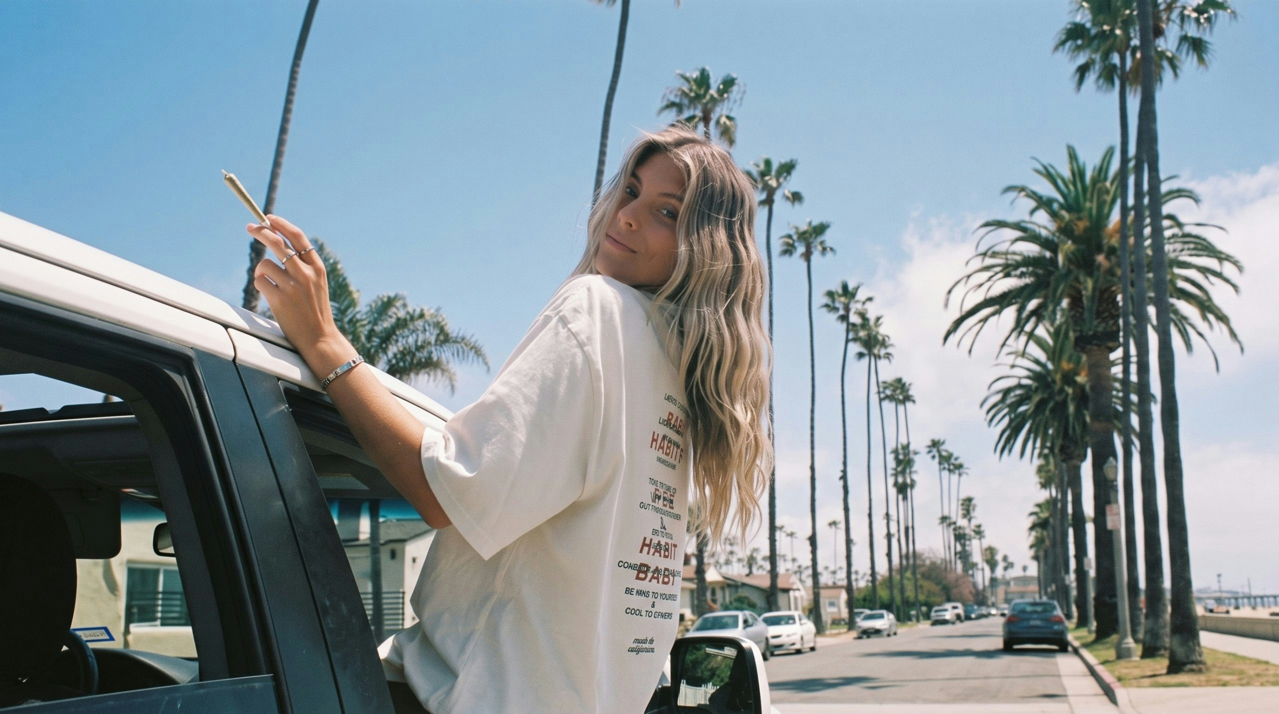 Blonde woman leaning out of a car window while holding a joint