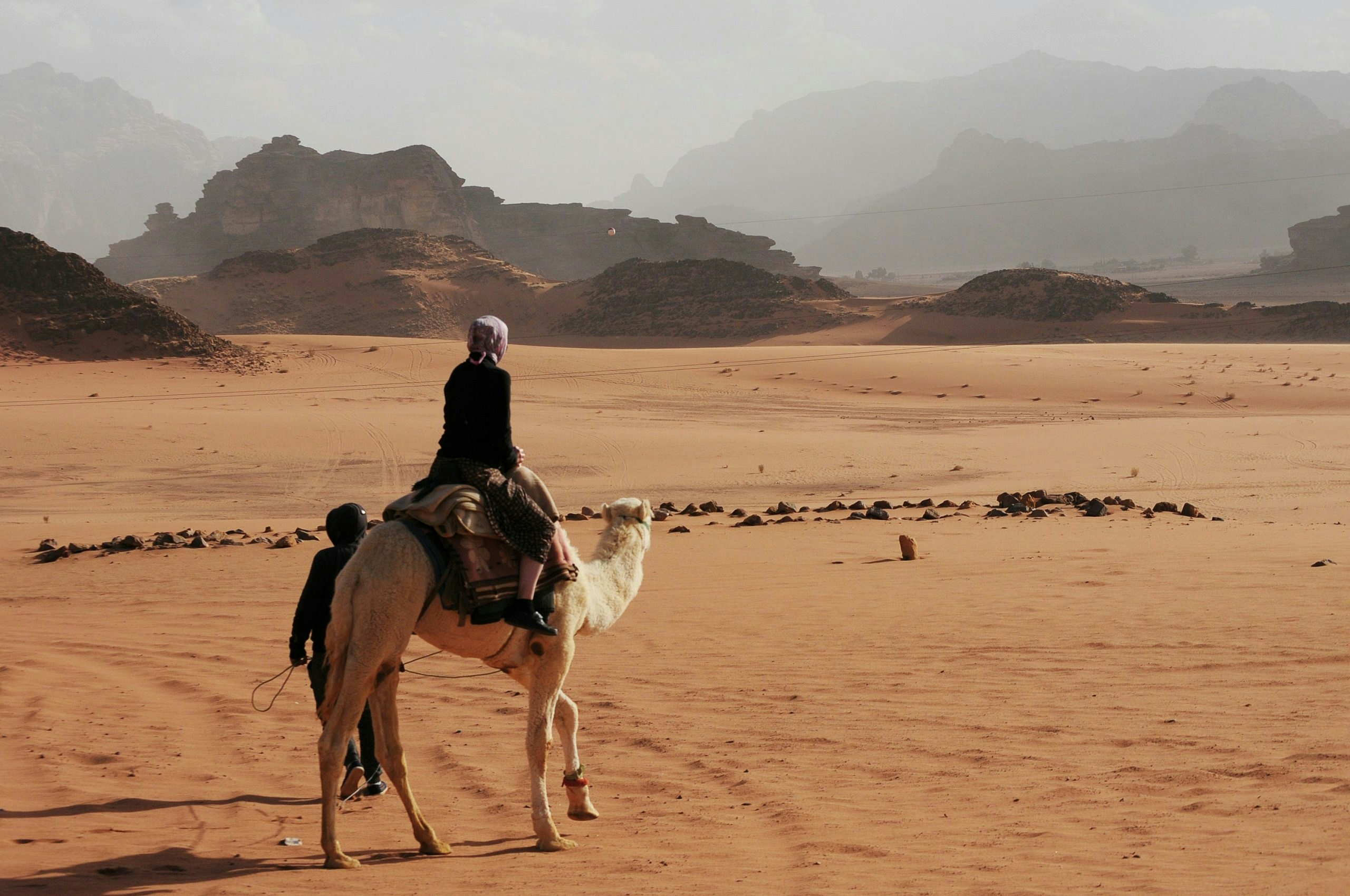 Person riding a camel through the desert in Jordan