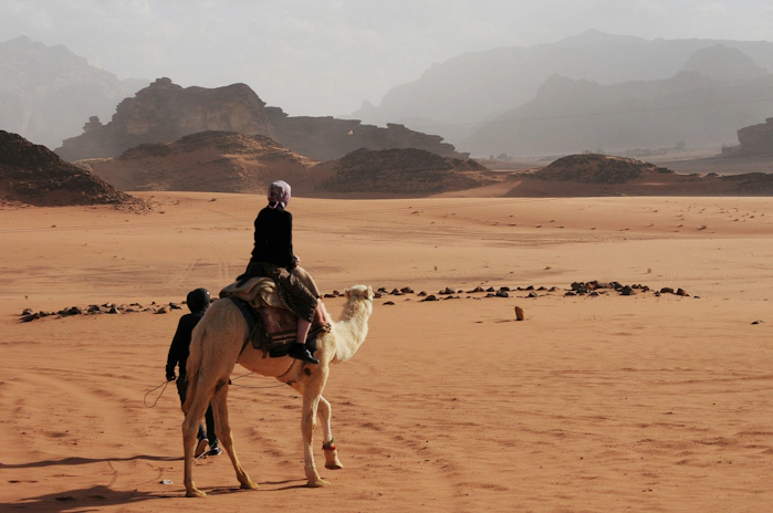 Person riding a camel through the desert in Jordan