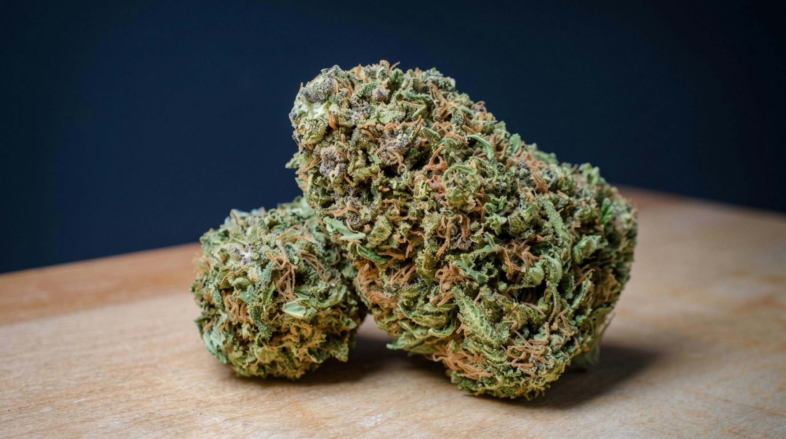 two cannabis buds over a wooden table