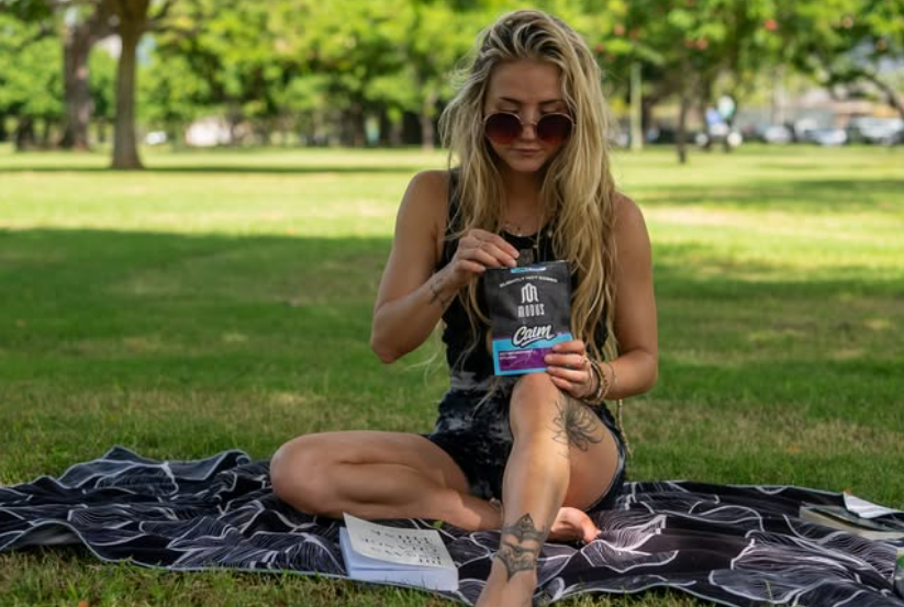 woman having a sns gummy from modus at the park